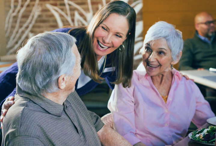 Senior living team member interacting with residents during a meal.