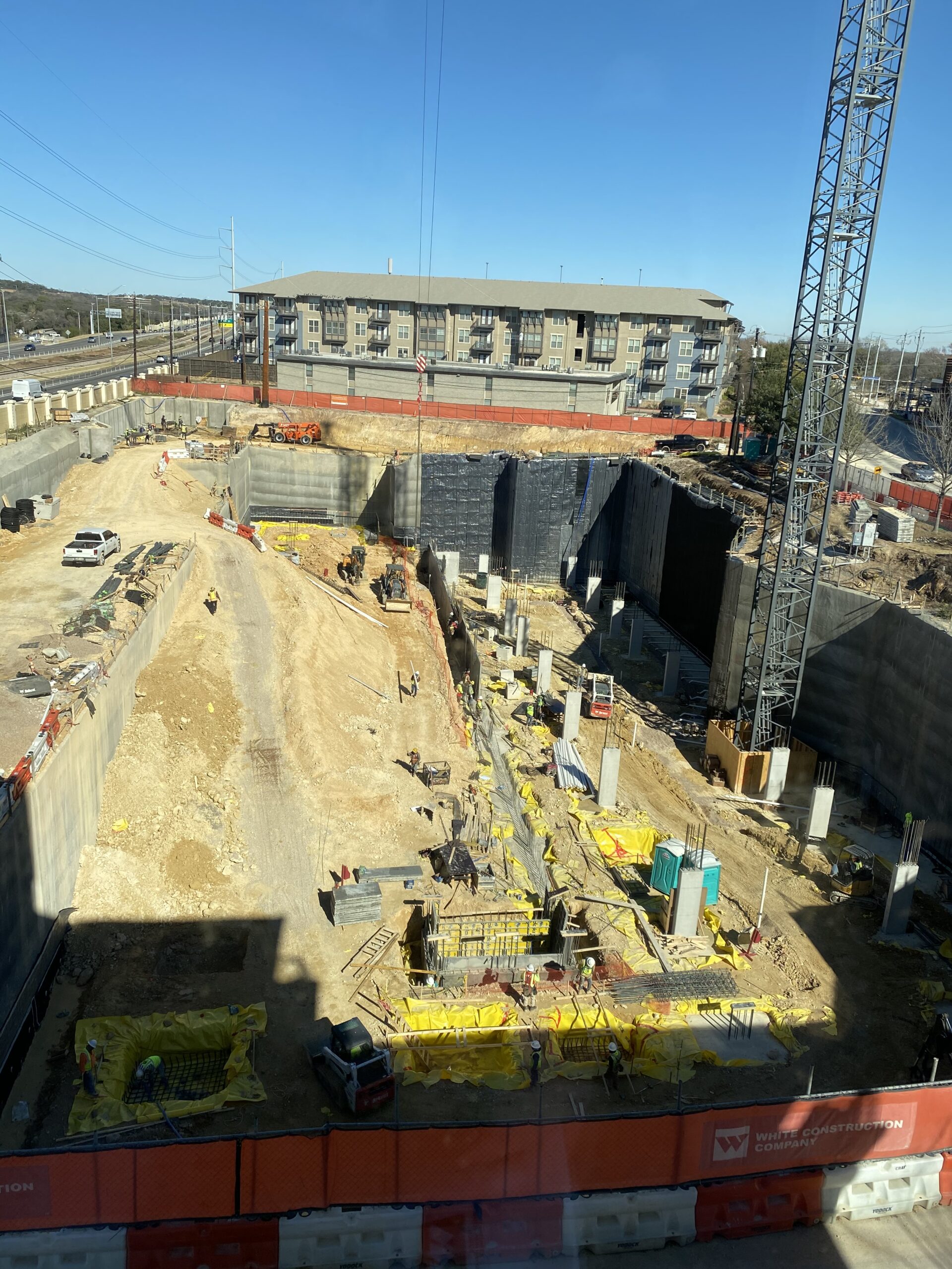 A building site in the daytime with a four-story building in the background, at Westminster Austin, Texas.