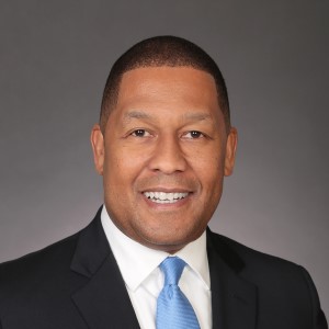 A headshot of a man, Greg Williams, smiling at the camera