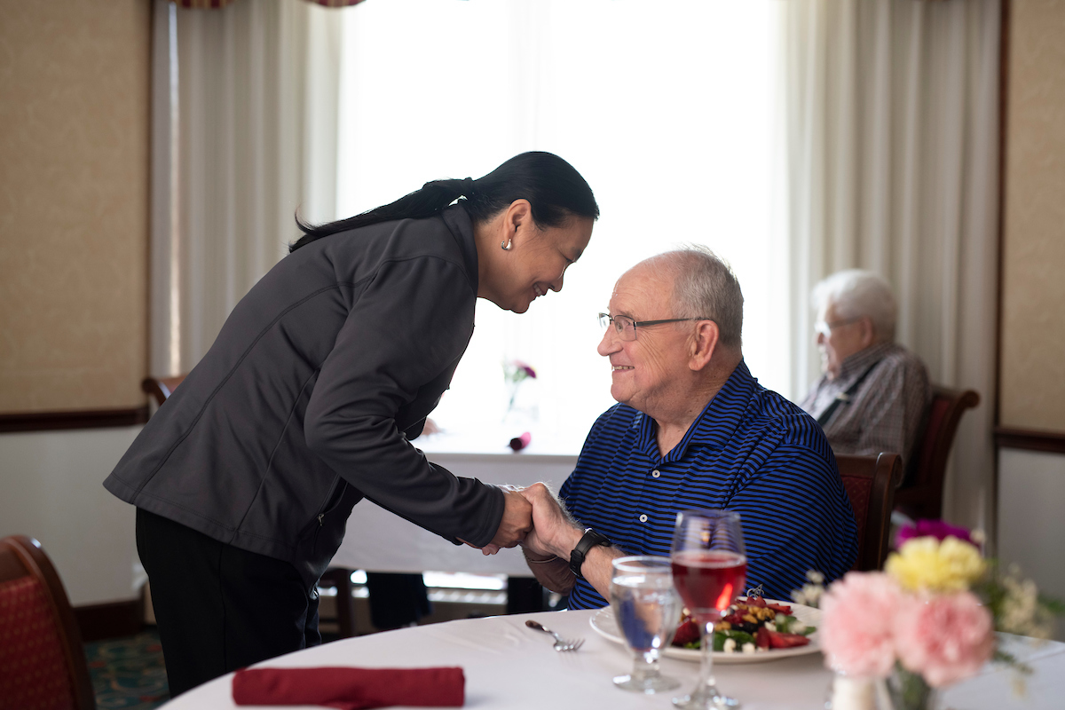 Community Employee and Senior in Dining Room